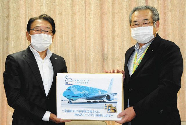 相川勝重町長（右）にチョコパイの入った段ボールを手渡す佐藤道雄副支店長＝芝山町役場で