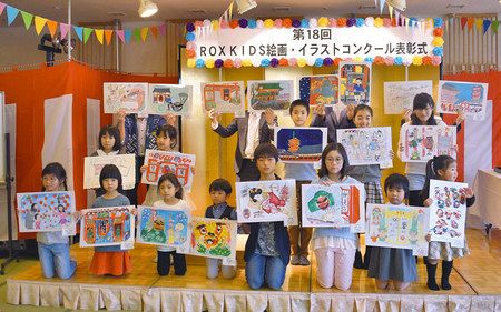 表彰式で、それぞれの入賞作品を掲げる子どもたち＝台東区で