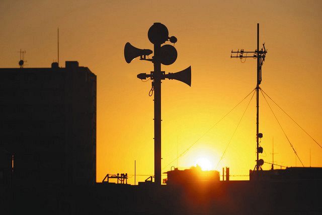夕焼けに浮かび上がる防災無線のスピーカー（中）＝２０日、東京都板橋区で