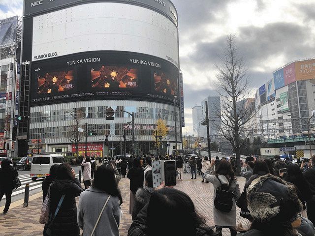 音楽グループ「ＢＴＳ」の応援広告を見上げる人ら＝新宿区新宿３丁目で（ユニカビジョン提供）