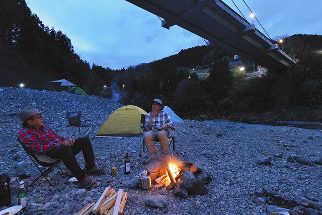 川井キャンプ場で暮れていく風景を眺めながらたき火を囲んで語り合う重信さん（右）と坂本記者