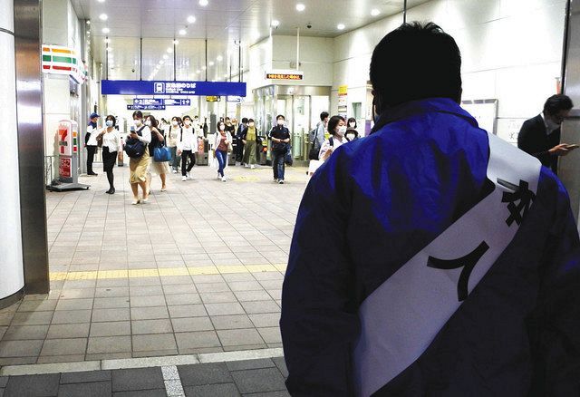 「本人」と書かれたタスキをかけ、駅前で支持を呼びかける候補予定者＝東京都内で