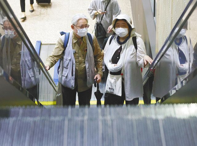 ＪＲ東京駅のエスカレーターで、難病の藤原佳世さん（右）を支えるように隣後方に立つ夫の康裕さん
