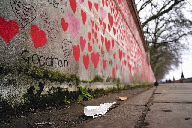 英ロンドンで今月１５日、新型コロナウイルス感染犠牲者を赤いハートで描いた「追悼の壁」のそばに落ちているマスク＝ＡＰ