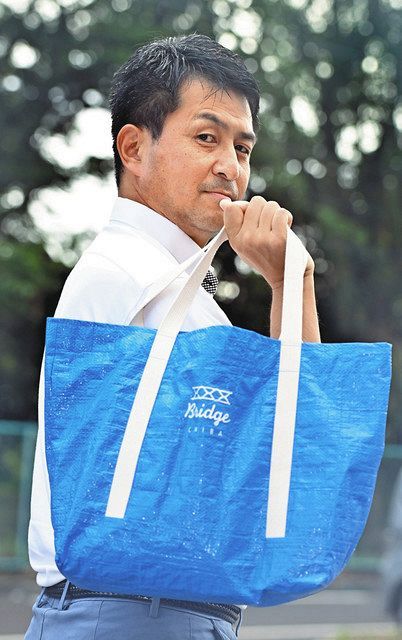 ブルーシートを再利用したトートバッグを手にする千葉テレビの福島浩之さん＝千葉市中央区で（潟沼義樹撮影）