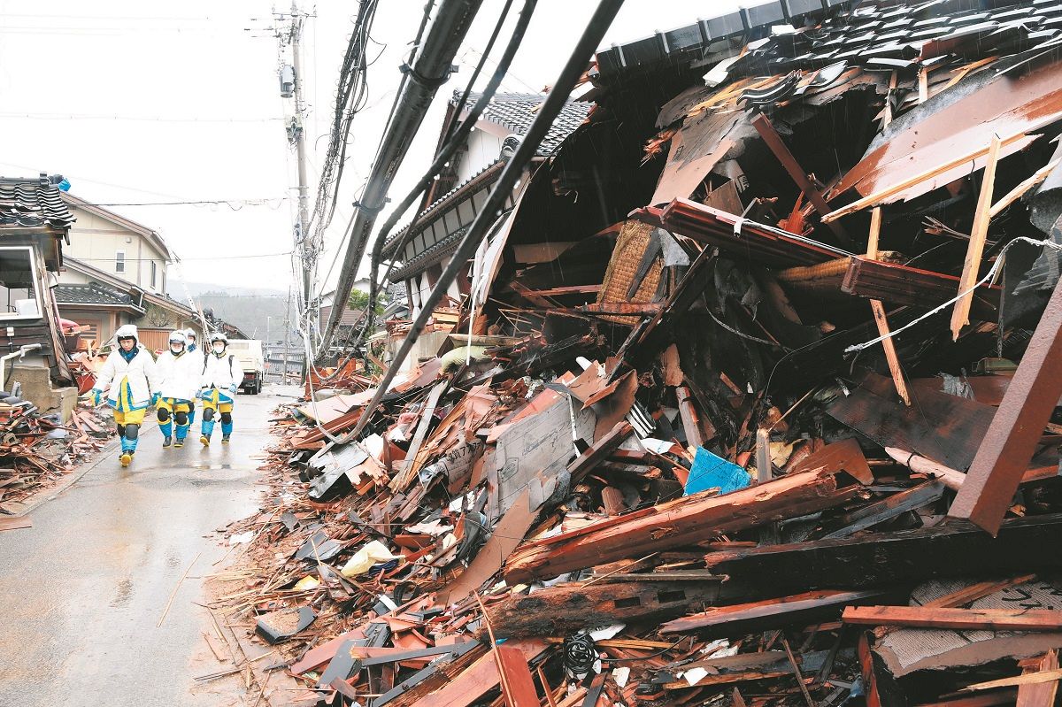 雨にぬれる倒壊した家屋。警察官らが辺りを見回る姿が見られた＝10日、石川県輪島市門前町道下で