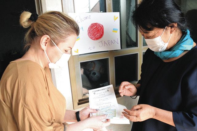 インナさん（左）に臨時の健康保険証などを手渡す太田恵美子さん＝４月２８日、横浜市青葉区で