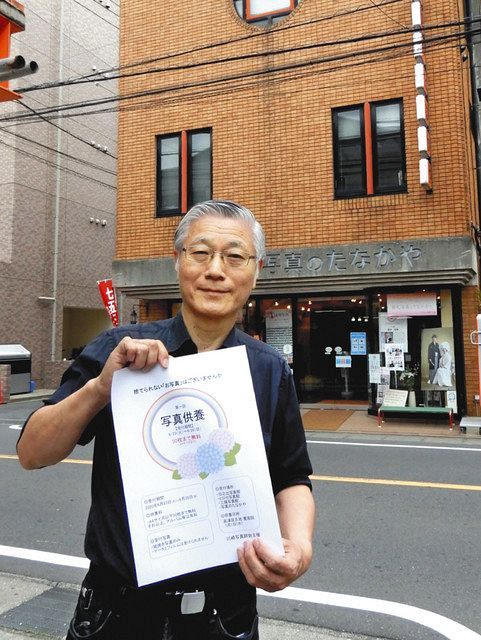 写真供養のポスターを掲げる鈴木克明さん＝高津区溝口で 