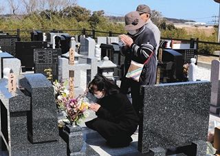 津波で亡くなった家族の眠る墓に手を合わせる女性ら＝浪江町の大平山霊園