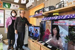 再開した仮設店舗に夫の真照さんと立つ滝本英子さん（左）