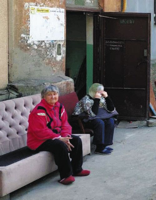 ウクライナ南東部マリウポリで４月２７日、壊れた自宅アパート前に座るアルトゥールさんの母（左）＝アルトゥールさん提供