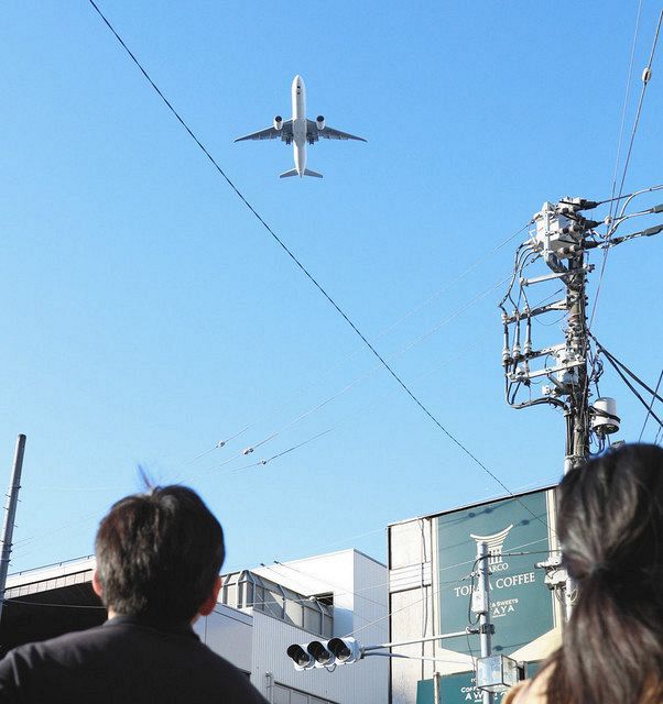 羽田空港の新飛行ルートで大井町駅周辺上空を飛行する航空機＝東京都品川区で
