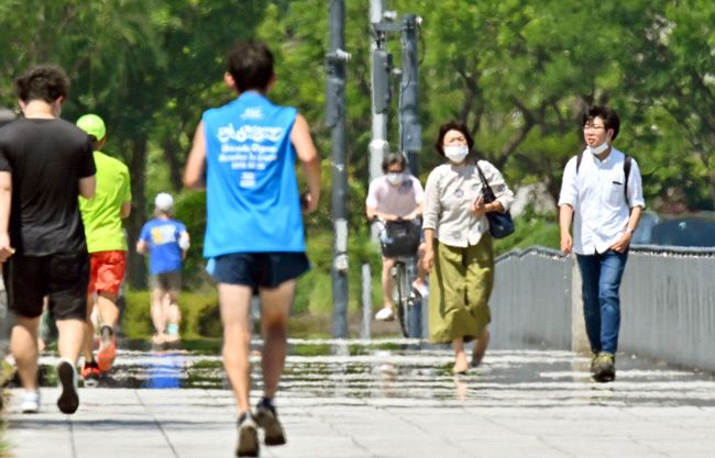 ［初日、３５．４℃］　都内で今年初の猛暑日となり、かげろうや逃げ水が現れた歩道を行き交う人たち＝6月25日、千代田区で、由木直子撮影