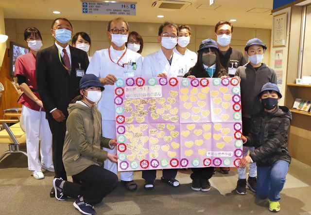 中村病院で、医療従事者への感謝のメッセージを手にする児童と医師ら＝墨田区で