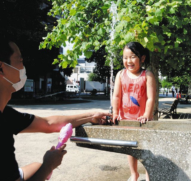 涼しさを感じようと、公園の水飲み場で戯れる親子＝千葉市中央区で
