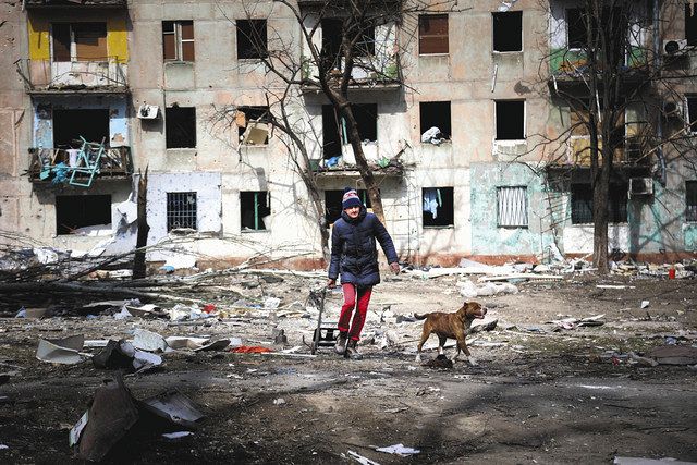 ３月２９日、ウクライナのマリウポリ郊外の親ロシア派支配地域で、破壊されたアパートの近くを犬と散歩する男性＝ＡＰ