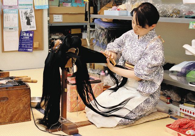 結い坊主と呼ばれる木製の台にかつらをのせて髪を結っていく