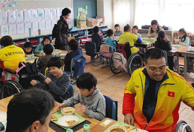 ベトナムのホストタウン国分寺市の小学校で２０１９年１月、給食を食べながら交流するベトナムのパワーリフティングのパラアスリートと児童ら＝市提供
