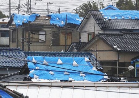 台風１９号の影響で強風にあおられる家屋の屋根に覆われているブルーシート＝１２日午前、千葉県館山市で