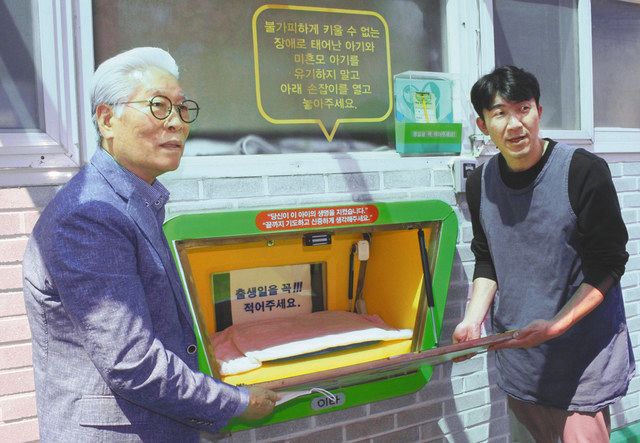 ソウルで４月、施設の外壁に設置された赤ちゃんポストを開く李鍾洛さん（左）ら