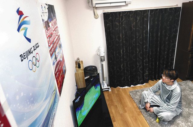 部屋に北京冬季五輪のポスターを張り、開会式のテレビ放映を見る徐浩予さん＝４日夜、熱海市で 