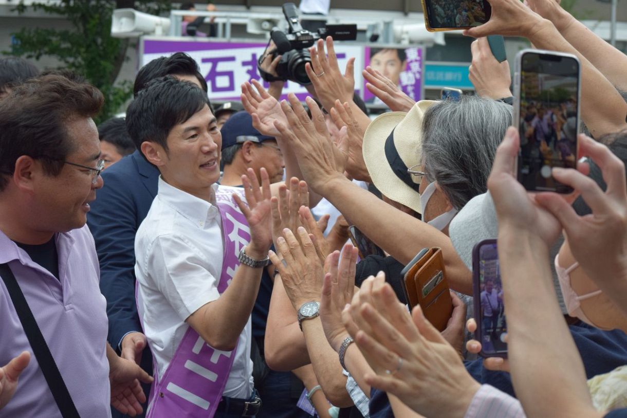 都知事選の街頭演説に集まった聴衆にハイタッチで応える石丸伸二氏（左から2人目、佐藤裕介撮影）