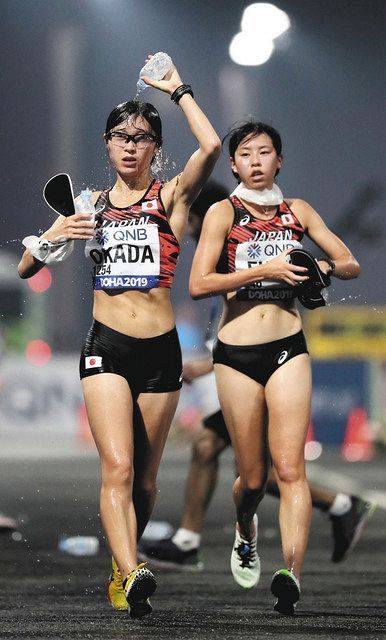 ２０１９年の世界選手権女子２０キロ競歩で、頭に水を掛けながらレースする日本代表の岡田久美子。右は藤井奈々子。東京五輪でも暑さ対策が課題となる＝ドーハで