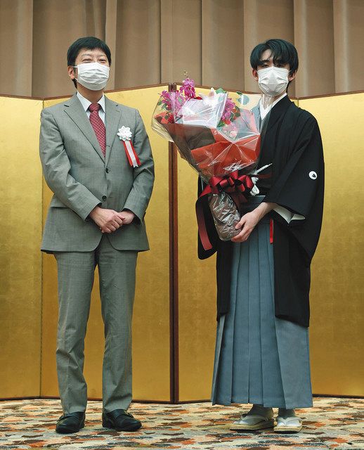 第６２期王位就位式で師匠の杉本昌隆八段（左）から花束を受け取る藤井聡太王位 