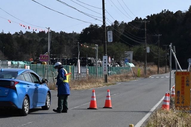 中間貯蔵施設のゲート前。奥に積まれているのは、汚染土が入った黒い土のう袋（フレコンバック）＝福島県双葉町で