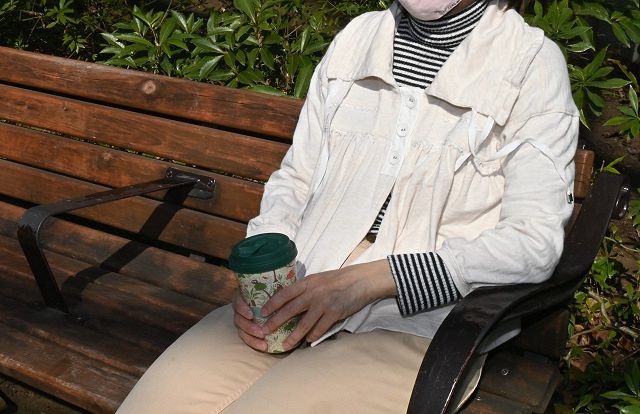 若くして亡くなった親友「みーたん」の形見の服を着て、ベンチに座る芹沢さん。「自分では選ばない、あの人のセンスだな」と思いをはせる