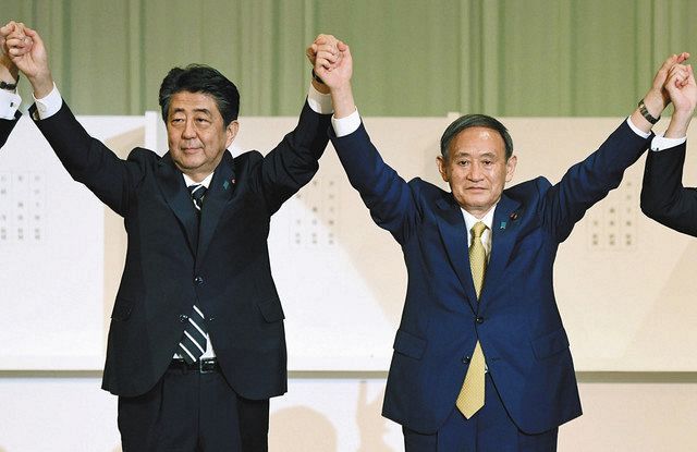 自民党総裁選を終え、安倍晋三首相（左）と手を取り合う菅義偉新総裁
