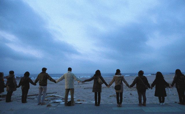 東日本大震災の犠牲者追悼と復興への願いを込め、夜明けの海に向かって手をつなぐ人たち＝２０１３年３月１０日
