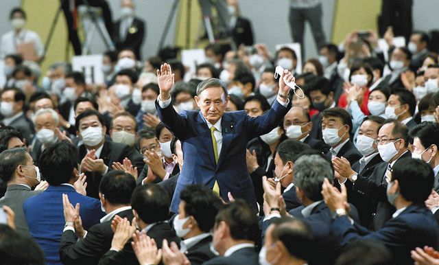 自民党の新総裁に選ばれ、手を挙げて祝福にこたえる菅義偉官房長官（中央）＝東京都内のホテルで