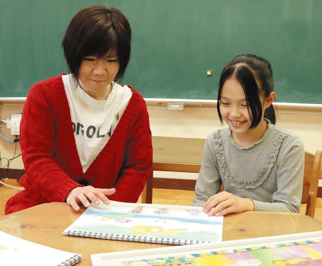 工藤さん（左）に描いた絵を見せる松原さん＝墨田区立第三寺島小学校で