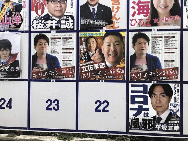 候補者の選挙ポスターが張られた掲示板。立花さんの両隣には出馬していない堀江さんの写真が並ぶ＝２５日、東京都内で