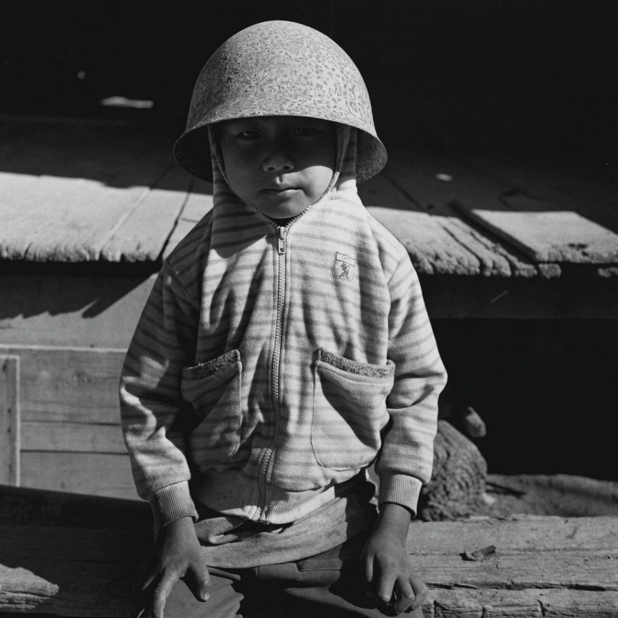 旧日本軍の兵士がかぶっていたヘルメットを頭に載せる少年