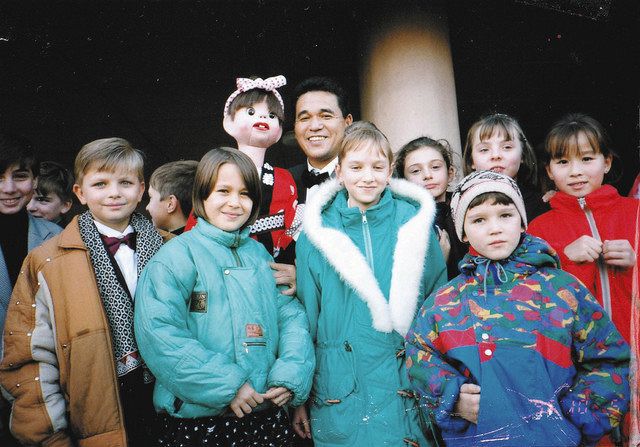 子どもたちに囲まれたゴローちゃんとしろたにさん＝１９９６年１０月、ロシア・オムスク市で（本人提供）

