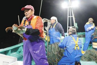漁船上で網に掛かった魚を手にする漁師小野春雄さん（左）。「トリチウムを海に流せば、魚は売れなくなる。説明が足りない」と話す＝10月21日、福島県で（写真はいずれも片山夏子撮影）