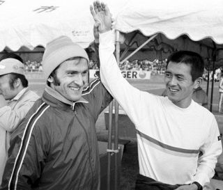 １９８０年１２月の福岡国際マラソンを制し、モスクワ五輪で優勝したチールピンスキー（左）に「おまえが一番」と手を上げられる瀬古利彦さん＝福岡市の平和台陸上競技場で