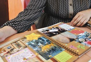 望月有花さんが出産までの記録をつづったスケッチブック。卵子を提供した女性がほほ笑む写真もある＝愛知県豊川市で