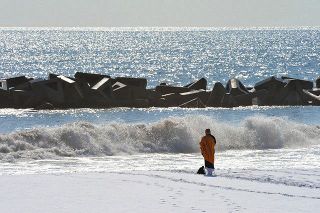 ２０１２年３月１１日本紙朝刊１面に掲載された写真。望月崇英さんは仙台市の海岸で波に向かって祈っていた＝同年３月４日撮影