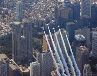 ５色のカラースモークを出して都心上空を飛行する航空自衛隊の「ブルーインパルス」。左は東京都庁（本社ヘリ「あさづる」から）