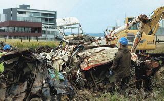 伝承館（右奥）の敷地近くでは津波で壊れた自動車の撤去作業が行われていた＝福島県双葉町で