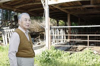 牛がいない牛舎の前で、１０年を振り返る坂本勝利さん＝福島県富岡町で
