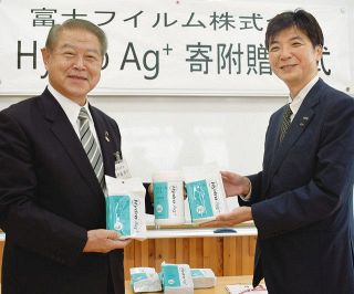 福沢小で行われた贈呈式で除菌クロスを示す富士フイルムの阿部さん（右）