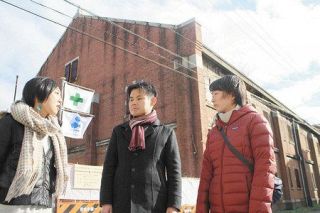 旧陸軍被服支廠の前で利活用案を語り合う（左から）瀬戸麻由さん、高田真さん、福岡奈織さん＝広島市南区で