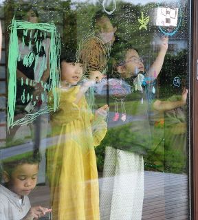 窓にお絵描きをする障害児モデルら＝５月、千葉県鴨川市で 
