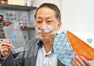 透明マスク「ミセルンデス」をつける東京和晒の滝沢一郎社長。左手に持つのは手ぬぐい用生地でつくった「らくなマスク」など