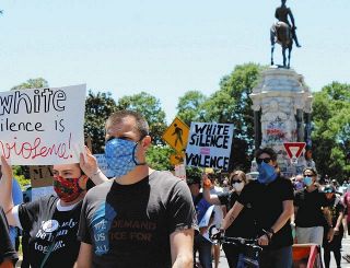 １３日、バージニア州リッチモンドで、「白人の沈黙は暴力だ」と書かれたプラカードを掲げ、リー将軍の銅像撤去を求めてデモ行進する人ら