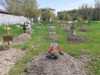 ウクライナ南東部マリウポリで、集合住宅の庭に埋められた市民の墓。日時は不明（ウラジミルさん提供）
